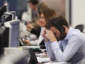 A worker on the IG Group's trading floor looks away from his screens in the City of London